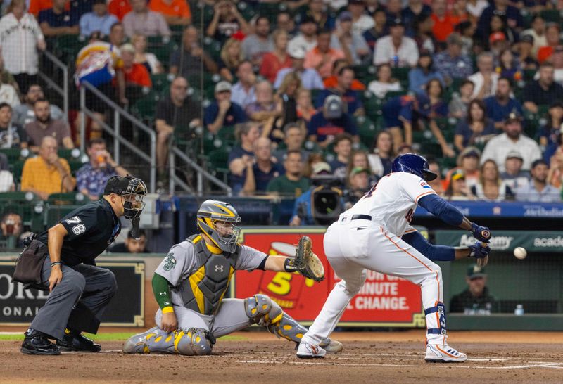 Sep 12, 2023; Houston, Texas, USA; Houston Astros designated hitter Yordan Alvarez (44) bunts safely and moves second baseman Jose Altuve (27) from first base to second base against the Oakland Athletics in the first inning at Minute Maid Park. Mandatory Credit: Thomas Shea-USA TODAY Sports