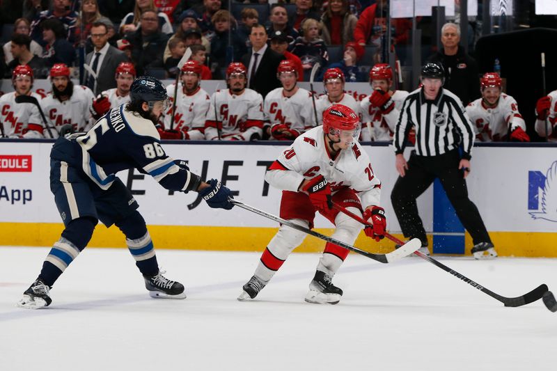 Dec 31, 2024; Columbus, Ohio, USA; Carolina Hurricanes left wing Sebastian Aho (20) controls the puck as Columbus Blue Jackets right wing Kirill Marchenko (86) trails the play during overtime at Nationwide Arena. Mandatory Credit: Russell LaBounty-Imagn Images