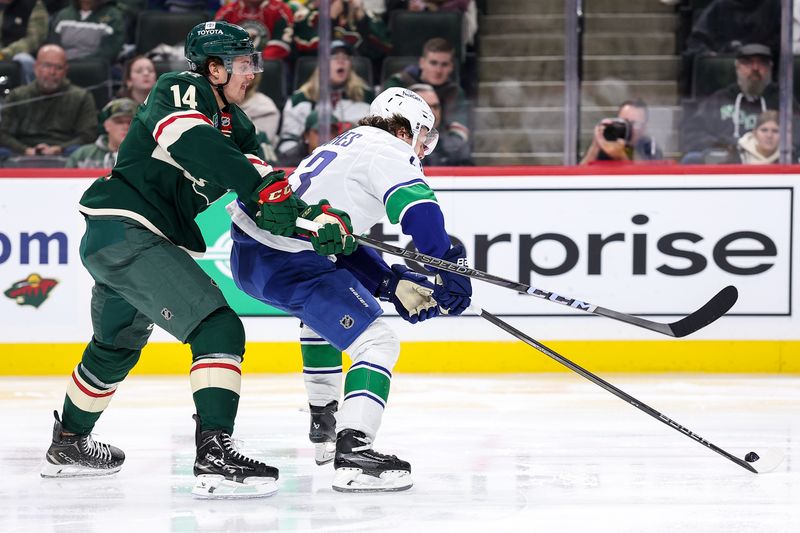 Dec 3, 2024; Saint Paul, Minnesota, USA; Vancouver Canucks defenseman Quinn Hughes (43) and Minnesota Wild center Joel Eriksson Ek (14) compete for the puck during the second period at Xcel Energy Center. Mandatory Credit: Matt Krohn-Imagn Images