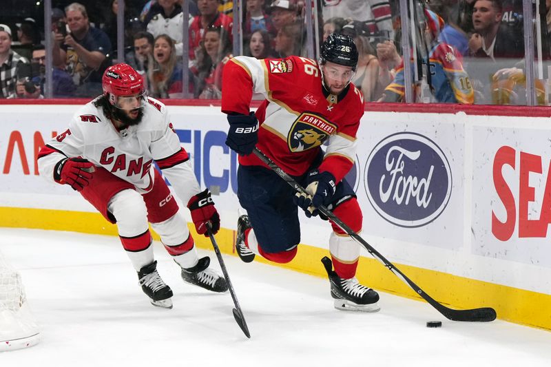 Nov 10, 2023; Sunrise, Florida, USA; Florida Panthers defenseman Uvis Balinskis (26) controls the puck away from Carolina Hurricanes defenseman Jalen Chatfield (5) during the second period at Amerant Bank Arena. Mandatory Credit: Jasen Vinlove-USA TODAY Sports