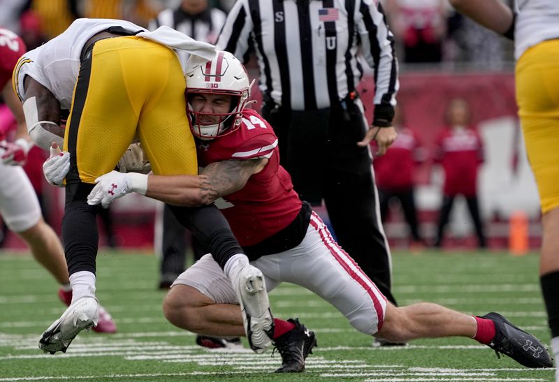 Oct 14, 2023; Madison, Wisconsin, USA; Wisconsin Badgers safety Preston Zachman (14) tackles Iowa Hawkeyes running back Leshon Williams (4) during the first quarter at Camp Randall Stadium. Mandatory Credit: Mark Hoffman-USA TODAY Sports