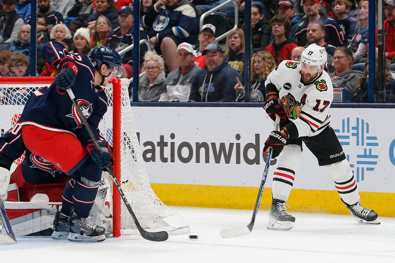 Nov 22, 2023; Columbus, Ohio, USA; Chicago Blackhawks leftt wing Nick Foligno (17) passes the puck as Columbus Blue Jackets defenseman Jake Bean (22) defends during the second period at Nationwide Arena. Mandatory Credit: Russell LaBounty-USA TODAY Sports