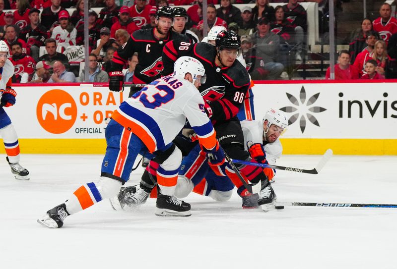 Apr 30, 2024; Raleigh, North Carolina, USA; New York Islanders center Casey Cizikas (53) and defenseman Adam Pelech (3) battle for the puck against Carolina Hurricanes left wing Teuvo Teravainen (86) during the first period in game five of the first round of the 2024 Stanley Cup Playoffs at PNC Arena. Mandatory Credit: James Guillory-USA TODAY Sports