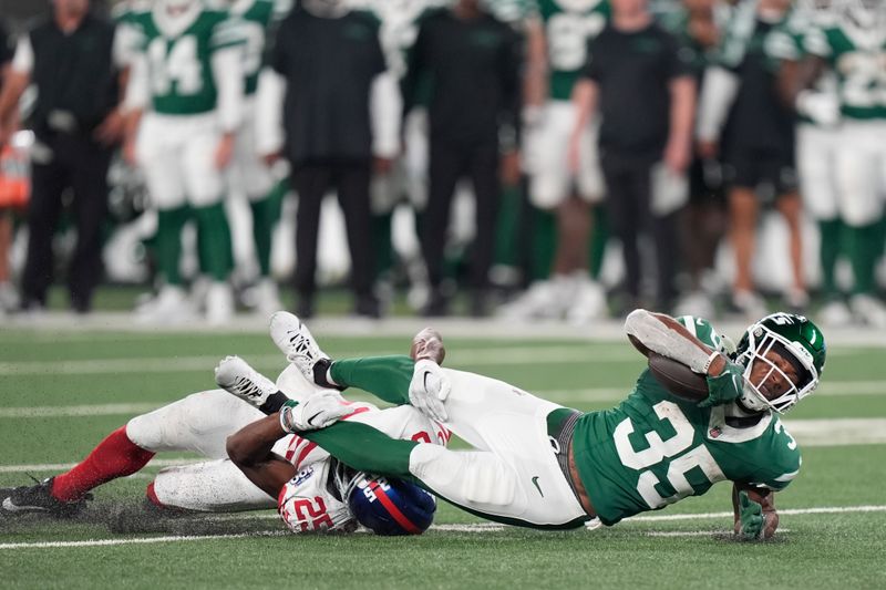 New York Giants' Tyrone Tracy Jr., left, tackles New York Jets' Xazavian Valladay during the first half of a preseason NFL football game, Saturday, Aug. 24, 2024, in East Rutherford, N.J. (AP Photo/Bryan Woolston)