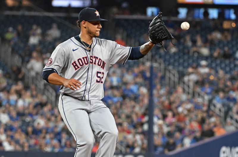 Jul 3, 2024; Toronto, Ontario, CAN; Houston Astros pitcher Bryan Abreu (52) fields an out at first base in the seventh inning against the Toronto Blue Jays at Rogers Centre. Mandatory Credit: Gerry Angus-USA TODAY Sports