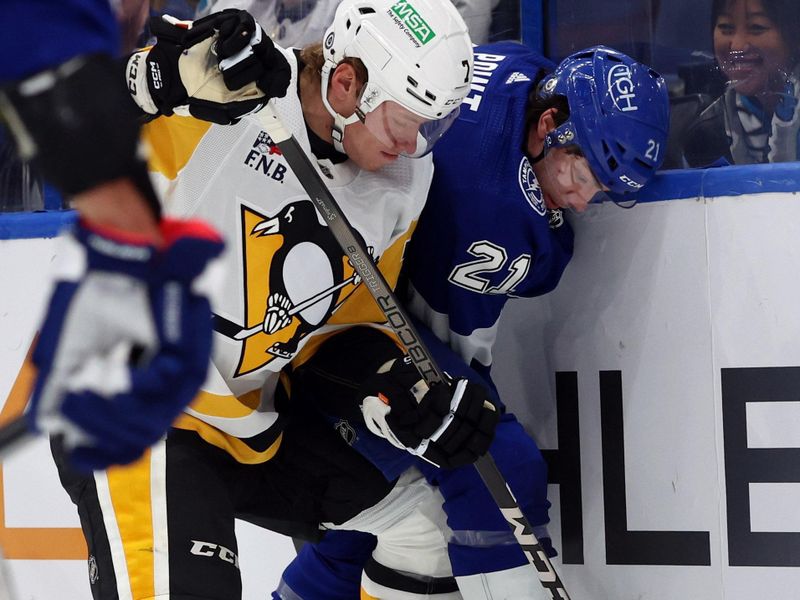 Dec 6, 2023; Tampa, Florida, USA; Tampa Bay Lightning center Brayden Point (21) and Pittsburgh Penguins defenseman John Ludvig (7) fight to control the puck during the third period at Amalie Arena. Mandatory Credit: Kim Klement Neitzel-USA TODAY Sports