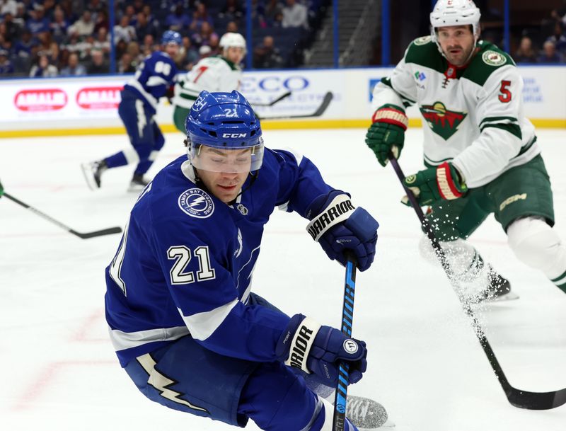 Oct 24, 2024; Tampa, Florida, USA; Tampa Bay Lightning center Brayden Point (21) skates with the puck as Minnesota Wild defenseman Jake Middleton (5) defends during the first period at Amalie Arena. Mandatory Credit: Kim Klement Neitzel-Imagn Images