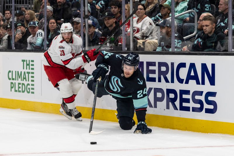 Oct 17, 2022; Seattle, Washington, USA; Seattle Kraken defenseman Jamie Oleksiak (24) goes to the ice while clearing the puck against Carolina Hurricanes forward Stefan Noesen (23) during the first period at Climate Pledge Arena. Mandatory Credit: Stephen Brashear-USA TODAY Sports