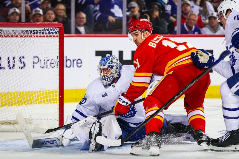 Feb 2, 2026; Calgary, Alberta, CAN; Toronto Maple Leafs goaltender Joseph Woll (60) and Calgary Flames center Mikael Backlund (11) battle for the puck during the second period at Scotiabank Saddledome. Mandatory Credit: Sergei Belski-Imagn Images