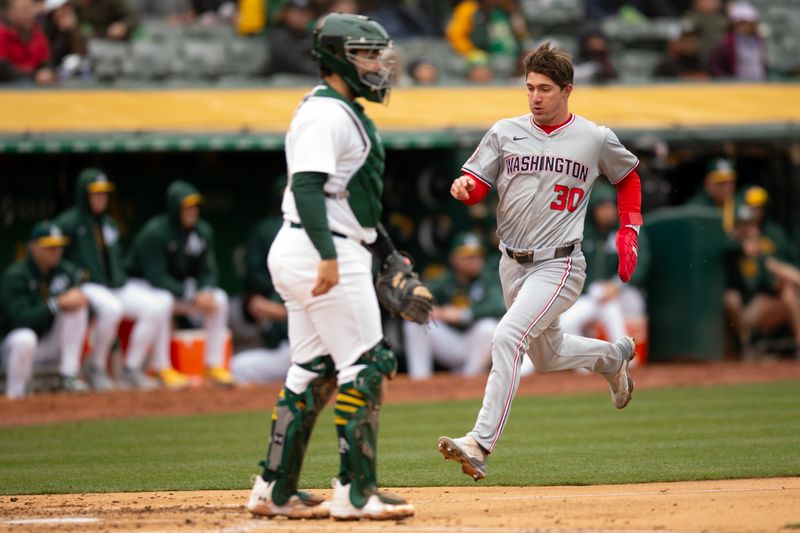 Apr 13, 2024; Oakland, California, USA; Washington Nationals center fielder Jacob Young (30) scores on a triple by CJ Abrams during the third inning as Oakland Athletics catcher Shea Langeliers (23) looks on at Oakland-Alameda County Coliseum. Mandatory Credit: D. Ross Cameron-USA TODAY Sports