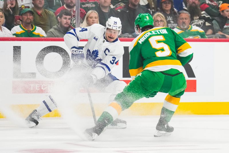 Nov 3, 2024; Saint Paul, Minnesota, USA; Toronto Maple Leafs center Auston Matthews (34) protects the puck from Minnesota Wild defenseman Jake Middleton (5) during the first period at Xcel Energy Center. Mandatory Credit: Brace Hemmelgarn-Imagn Images