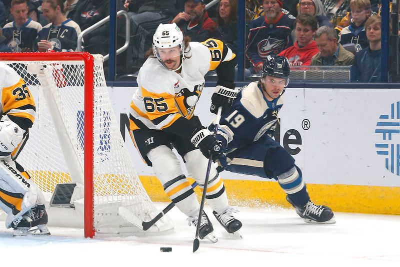 Nov 15, 2024; Columbus, Ohio, USA; Pittsburgh Penguins defenseman Erik Karlsson (65) and Columbus Blue Jackets center Adam Fantilli (19) battle for a loose puck during the first period at Nationwide Arena. Mandatory Credit: Russell LaBounty-Imagn Images