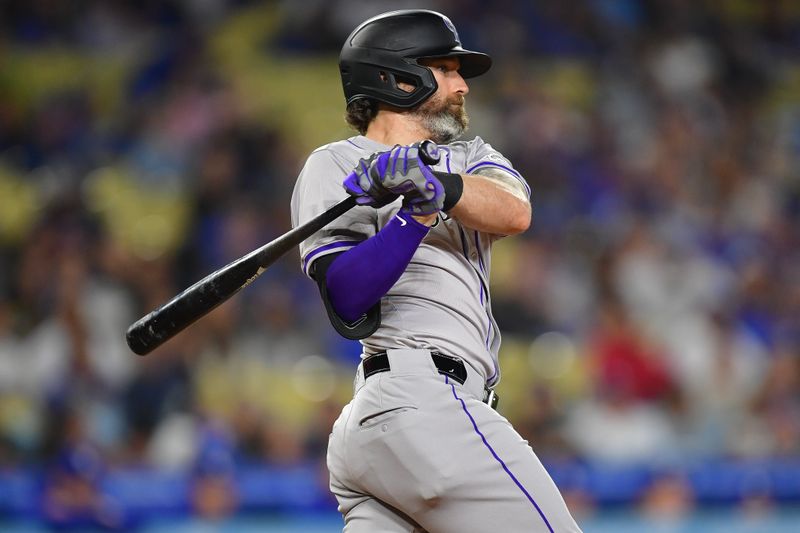 May 31, 2024; Los Angeles, California, USA; Colorado Rockies left fielder Jake Cave (11) hits a triple against the Los Angeles Dodgers during the ninth inning at Dodger Stadium. Mandatory Credit: Gary A. Vasquez-USA TODAY Sports