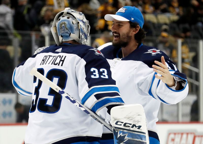 Jan 13, 2023; Pittsburgh, Pennsylvania, USA;  Winnipeg Jets goaltenders David Rittich (33) and Connor Hellebuyck (37) celebrate after defeating the Pittsburgh Penguins at PPG Paints Arena. The Jets won 4-1. Mandatory Credit: Charles LeClaire-USA TODAY Sports