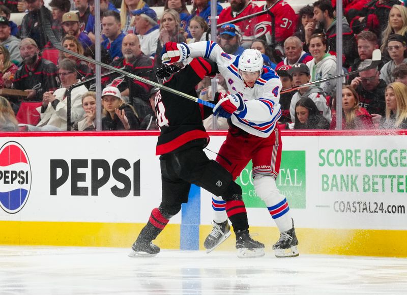 Apr 12, 2025; Raleigh, North Carolina, USA;  Carolina Hurricanes center Seth Jarvis (24) checks New York Rangers defenseman Braden Schneider (4) during the first period at Lenovo Center. Mandatory Credit: James Guillory-Imagn Images