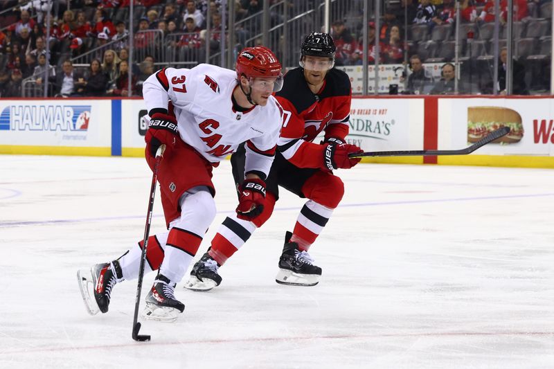 Nov 21, 2024; Newark, New Jersey, USA; Carolina Hurricanes right wing Andrei Svechnikov (37) skates with the puck against New Jersey Devils defenseman Dougie Hamilton (7) during the first period at Prudential Center. Mandatory Credit: Ed Mulholland-Imagn Images