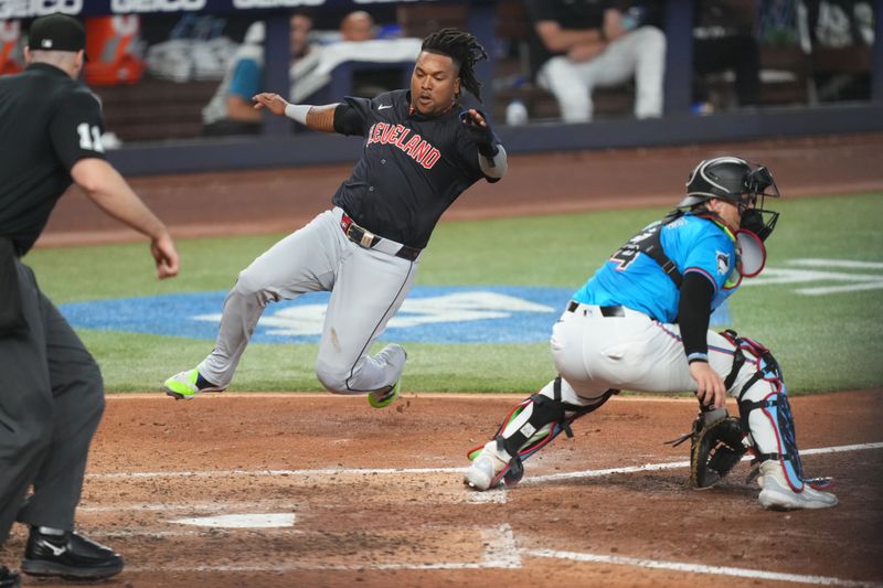 Jun 9, 2024; Miami, Florida, USA; Cleveland Guardians third baseman José Ramírez (11) slides in safe at home plate as Miami Marlins catcher Nick Fortes (4) awaits the throw in the sixth inning at loanDepot Park. Mandatory Credit: Jim Rassol-USA TODAY Sports