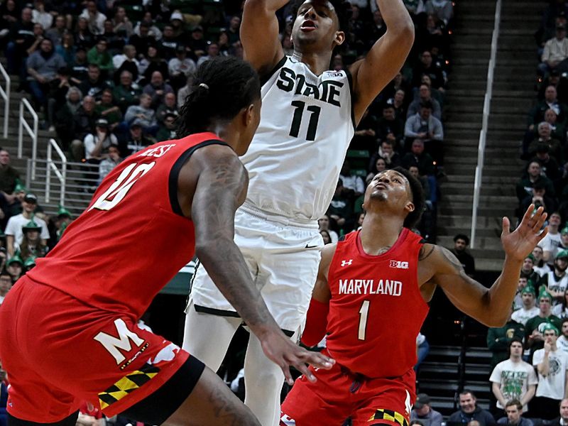 Feb 7, 2023; East Lansing, Michigan, USA;  Michigan State Spartans guard A.J. Hoggard (11) splits the defense, shooting between Maryland Terrapins forward Patrick Emilien (15) and guard Jahmir Young (1) in the second half at Jack Breslin Student Events Center. Mandatory Credit: Dale Young-USA TODAY Sports