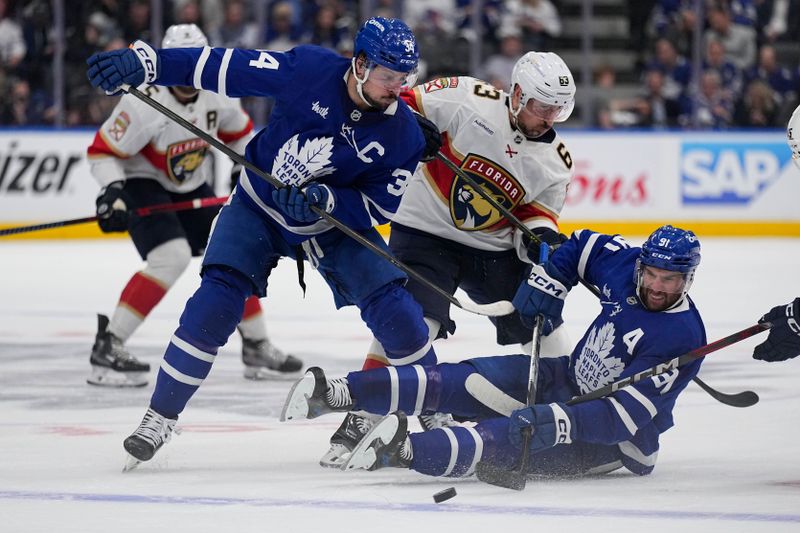 May 14, 2025; Toronto, Ontario, CAN; Toronto Maple Leafs forward Auston Matthews (34) and forward John Tavares (91)  and Florida Panthers forward Brad Marchand (63) battle for a puck during the second period of game five of the second round of the 2025 Stanley Cup Playoffs at Scotiabank Arena. Mandatory Credit: John E. Sokolowski-Imagn Images