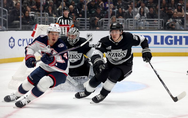 Nov 9, 2024; Los Angeles, California, USA; Columbus Blue Jackets center Cole Sillinger (4) and Los Angeles Kings defenseman Jordan Spence (21) chase a loose puck during the first period at Crypto.com Arena. Mandatory Credit: Jason Parkhurst-Imagn Images