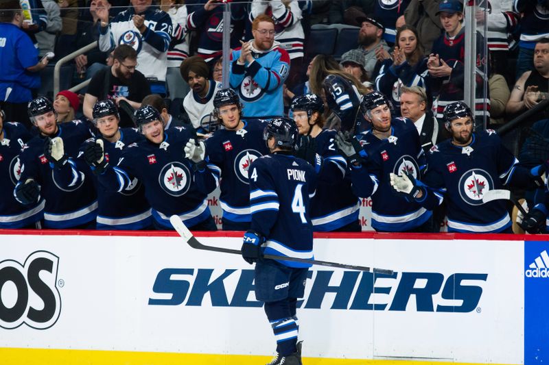 Jan 16, 2024; Winnipeg, Manitoba, CAN; Winnipeg Jets defenseman Neal Pionk (4) is congratulated by his teammates on his goal against the New York Islanders during the second period at Canada Life Centre. Mandatory Credit: Terrence Lee-USA TODAY Sports