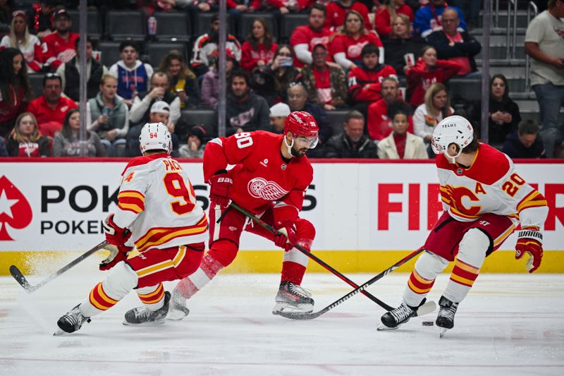 Nov 27, 2024; Detroit, Michigan, USA; Detroit Red Wings center Joe Veleno (90) brings the puck up ice against Calgary Flames defenseman Brayden Pachal (94) and center Blake Coleman (20) during the second period at Little Caesars Arena. Mandatory Credit: Tim Fuller-Imagn Images