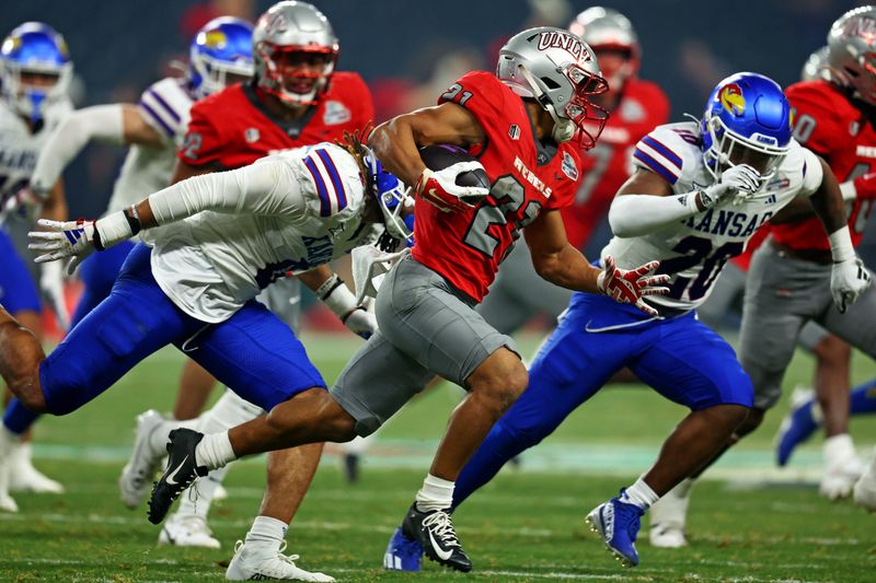 Dec 26, 2023; Phoenix, AZ, USA; UNLV Rebels wide receiver Jacob De Jesus (21) runs the ball against Kansas Jayhawks cornerback Kwinton Lassiter (8) and linebacker Donovan Gaines (20) during the second half in the Guaranteed Rate Bowl at Chase Field. Mandatory Credit: Mark J. Rebilas-USA TODAY Sports