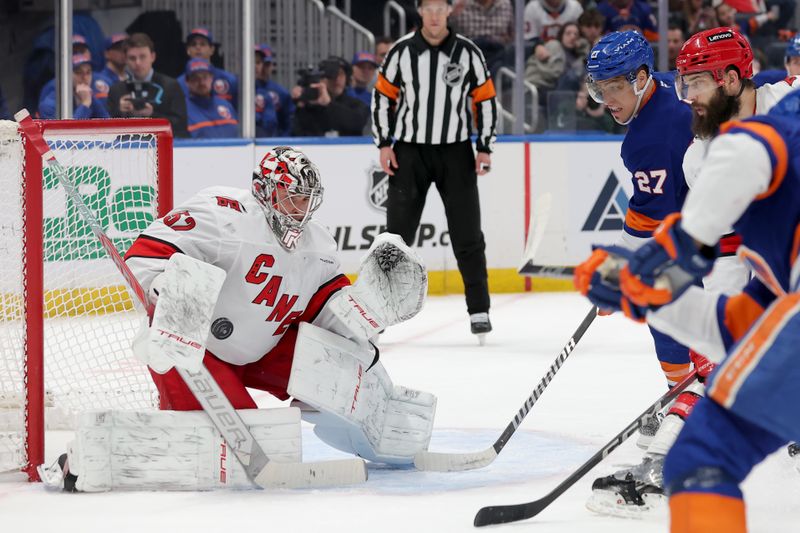 Jan 25, 2025; Elmont, New York, USA; Carolina Hurricanes goaltender Pyotr Kochetkov (52) makes a save in front of New York Islanders left wing Anders Lee (27) and Hurricanes defenseman Brent Burns (8) during the first period at UBS Arena. Mandatory Credit: Brad Penner-Imagn Images