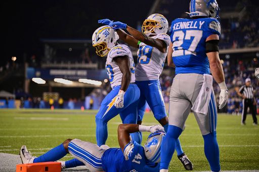 Los Angeles Chargers wide receiver Jaylen Johnson (39) celebrates with running back Kimani Vidal (30) in front of Detroit Lions linebacker Anthony Pittman (41) and safety Ian Kennelly (27) after Vidal's touchdown in the second half of the Pro Football Hall of Fame NFL preseason game Thursday, July 31, 2025, in Canton, Ohio. (AP Photo/David Dermer)