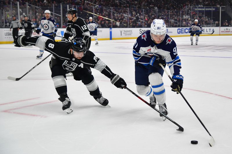 Dec 13, 2023; Los Angeles, California, USA; Winnipeg Jets center Cole Perfetti (91) moves the puck against Los Angeles Kings defenseman Drew Doughty (8) during the first period at Crypto.com Arena. Mandatory Credit: Gary A. Vasquez-USA TODAY Sports