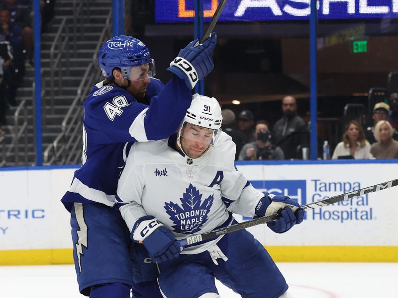 Apr 9, 2025; Tampa, Florida, USA; Tampa Bay Lightning defenseman Nick Perbix (48) and Toronto Maple Leafs center John Tavares (91) fight to control the puck during the second period at Amalie Arena. Mandatory Credit: Kim Klement Neitzel-Imagn Images