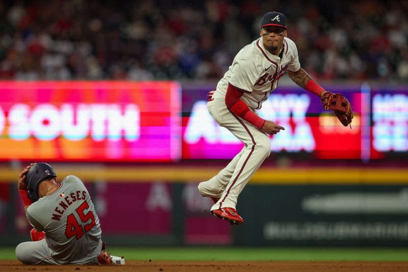 May 28, 2024; Atlanta, Georgia, USA; Atlanta Braves shortstop Orlando Arcia (11) turns a double play over Washington Nationals first baseman Joey Meneses (45) in the seventh inning at Truist Park. Mandatory Credit: Brett Davis-USA TODAY Sports