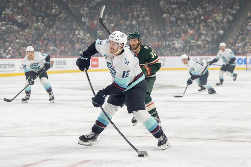 Oct 12, 2024; Saint Paul, Minnesota, USA; Seattle Kraken left wing Tye Kartye (12) shoots while Minnesota Wild right wing Ryan Hartman (38) in pursues in the first period at Xcel Energy Center. Mandatory Credit: Matt Blewett-Imagn Images