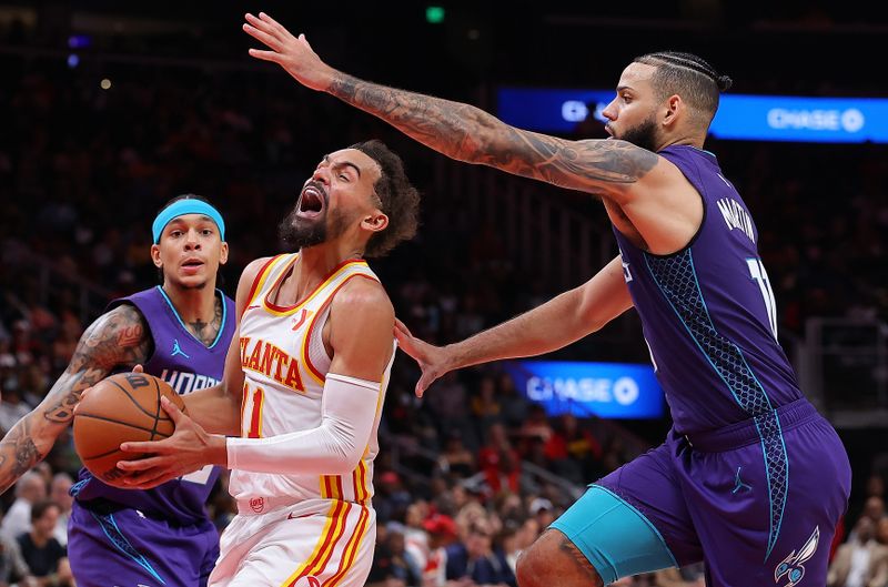 ATLANTA, GEORGIA - OCTOBER 25:  Trae Young #11 of the Atlanta Hawks drives between Cody Martin #11 and Tre Mann #23 of the Charlotte Hornets during the third quarter at State Farm Arena on October 25, 2024 in Atlanta, Georgia.  NOTE TO USER: User expressly acknowledges and agrees that, by downloading and/or using this photograph, user is consenting to the terms and conditions of the Getty Images License Agreement.  (Photo by Kevin C. Cox/Getty Images)