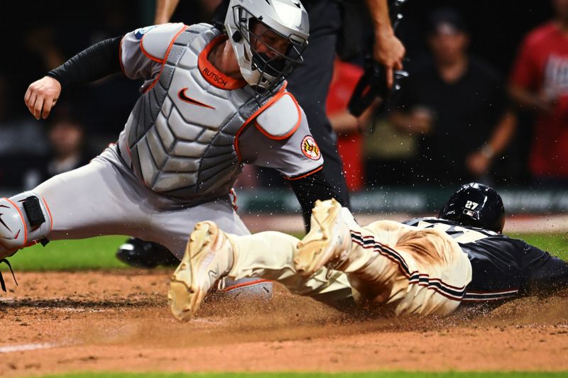 Aug 2, 2024; Cleveland, Ohio, USA; Cleveland Guardians catcher Austin Hedges (27) scores as Baltimore Orioles catcher Adley Rutschman (35) is late with the tag during the sixth inning at Progressive Field. Mandatory Credit: Ken Blaze-USA TODAY Sports