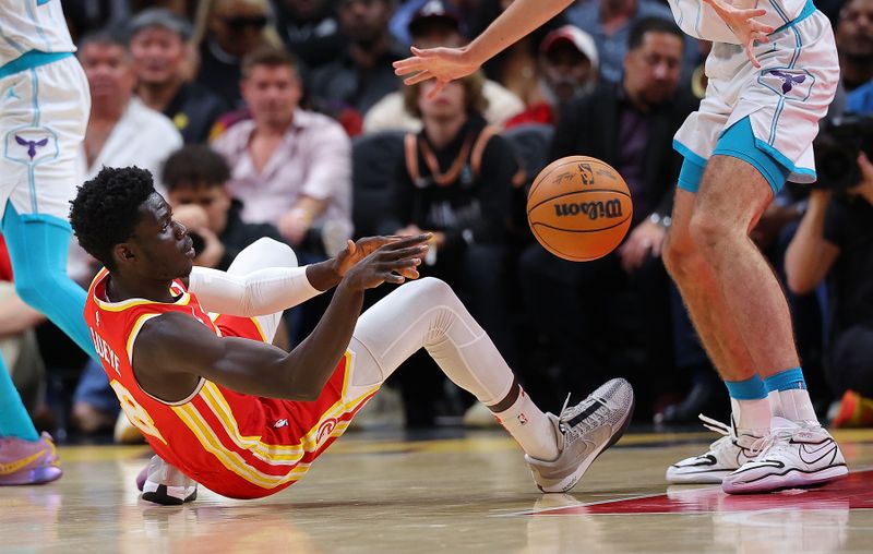 ATLANTA, GEORGIA - APRIL 10:  Mouhamed Gueye #18 of the Atlanta Hawks passes the ball as he falls to the floor against the Charlotte Hornets during the third quarter at State Farm Arena on April 10, 2024 in Atlanta, Georgia.  NOTE TO USER: User expressly acknowledges and agrees that, by downloading and/or using this photograph, user is consenting to the terms and conditions of the Getty Images License Agreement.  (Photo by Kevin C. Cox/Getty Images)