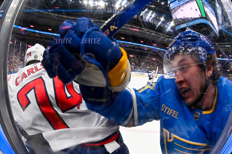 Jan 20, 2024; St. Louis, Missouri, USA;  St. Louis Blues left wing Jake Neighbours (63) checks Washington Capitals defenseman John Carlson (74) during the second period at Enterprise Center. Mandatory Credit: Jeff Curry-USA TODAY Sports