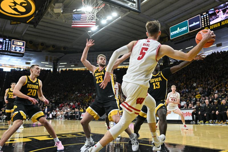 Feb 17, 2024; Iowa City, Iowa, USA; Wisconsin Badgers forward Tyler Wahl (5) passes the ball as Iowa Hawkeyes forward Payton Sandfort (20) and forward Ben Krikke (23) and forward Ladji Dembele (13) defend during the first half at Carver-Hawkeye Arena. Mandatory Credit: Jeffrey Becker-USA TODAY Sports