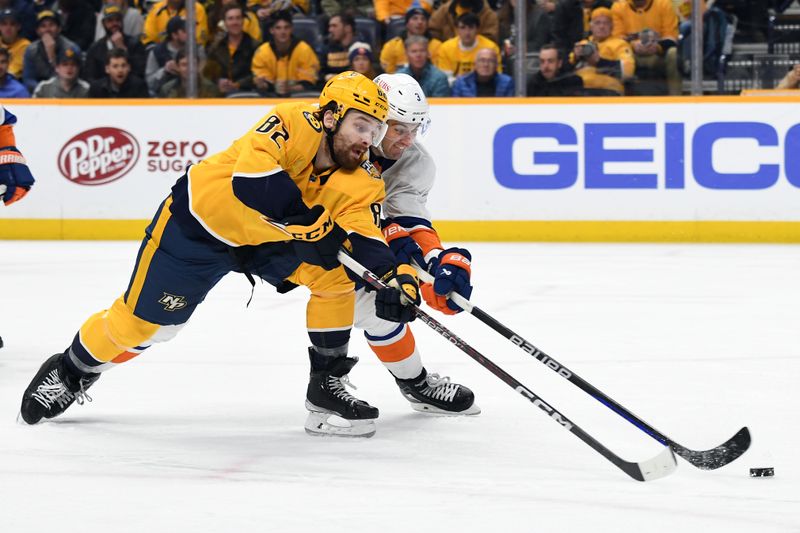 Jan 13, 2024; Nashville, Tennessee, USA; Nashville Predators center Tommy Novak (82) loses control of the puck against New York Islanders defenseman Adam Pelech (3) during the third period at Bridgestone Arena. Mandatory Credit: Christopher Hanewinckel-USA TODAY Sports