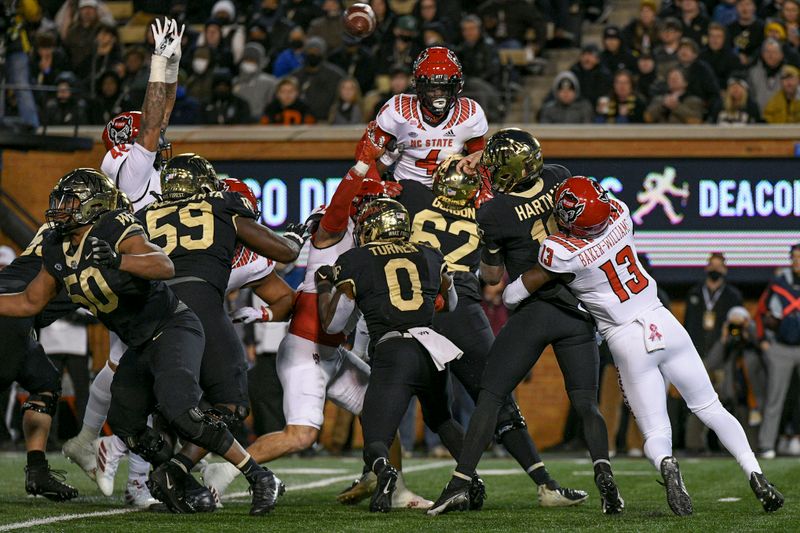 Nov 13, 2021; Winston-Salem, North Carolina, USA; Wake Forest Demon Deacons quarterback Sam Hartman (10) is hit as he throws a pass against the North Carolina State Wolfpack during the first half at Truist Field. Mandatory Credit: William Howard-USA TODAY Sports