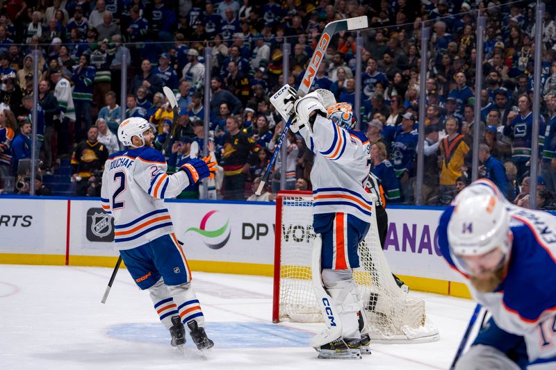 May 20, 2024; Vancouver, British Columbia, CAN;  As Edmonton Oilers defenseman Mattias Ekholm (14) picks up the game puck defenseman Evan Bouchard (2) and goalie Stuart Skinner (74) celebrate their victory over the Vancouver Canucks in game seven of the second round of the 2024 Stanley Cup Playoffs at Rogers Arena. Mandatory Credit: Bob Frid-USA TODAY Sports