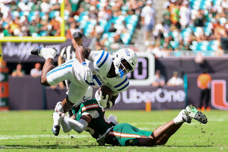 Nov 2, 2024; Miami Gardens, Florida, USA; Duke Blue Devils running back Peyton Jones (5) runs with the football against Miami Hurricanes defensive back Jadais Richard (25) during the second quarter at Hard Rock Stadium. Mandatory Credit: Sam Navarro-Imagn Images