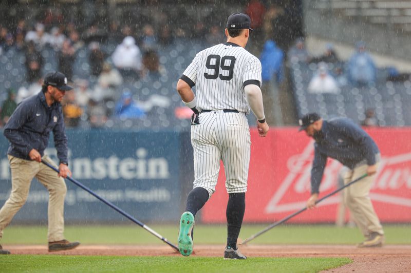 May 5, 2024; Bronx, New York, USA; New York Yankees center fielder Aaron Judge (99) runs on the field as members of the ground crew work on the infield during the seventh inning against the Detroit Tigers at Yankee Stadium. Mandatory Credit: Vincent Carchietta-USA TODAY Sports