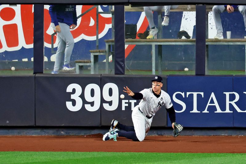 Oct 30, 2024; Bronx, New York, USA; New York Yankees outfielder Aaron Judge (99) jumps into the outfield wall to catch a fly ball during the fourth inning against the Los Angeles Dodgers during game five of the 2024 MLB World Series at Yankee Stadium. Mandatory Credit: James Lang-Imagn Images