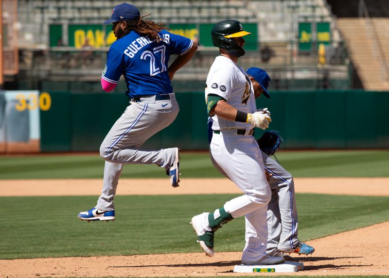 Sep 6, 2023; Oakland, California, USA; Toronto Blue Jays first baseman Vladimir Guerrero Jr. (27) beats Oakland Athletics pinch hitter Seth Brown (15) to first base on a ground ball during the eighth inning at Oakland-Alameda County Coliseum. Mandatory Credit: D. Ross Cameron-USA TODAY Sports