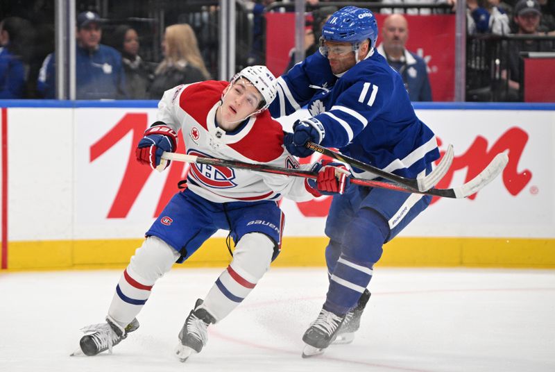 Sep 26, 2024; Toronto, Ontario, CAN;  Toronto Maple Leafs forward Max Domi (11) earns a two minute penalty for crosschecking Montreal Canadiens forward Lane Hutson (48) in the first period at Scotiabank Arena. Mandatory Credit: Dan Hamilton-Imagn Images