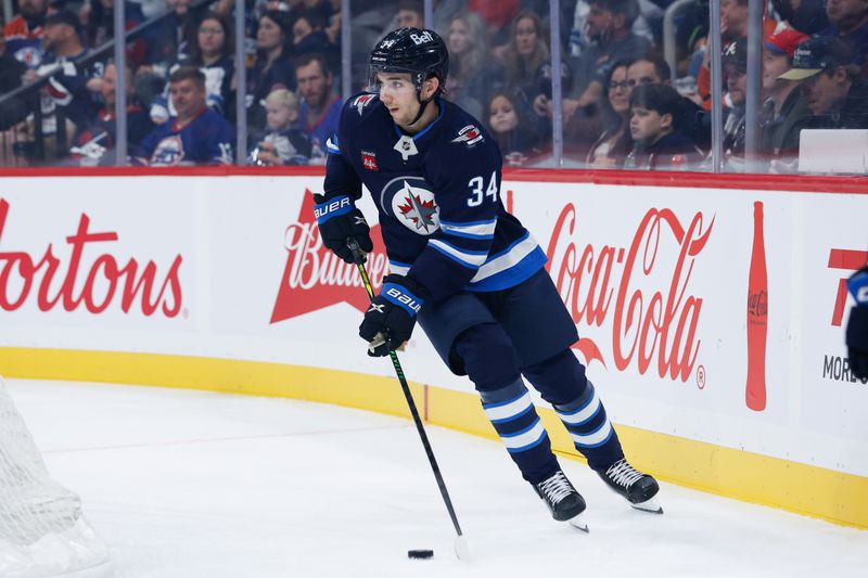 Sep 23, 2025; Winnipeg, Manitoba, CAN;  Winnipeg Jets defenseman Ville Heinola (34) looks to make a pass against the Edmonton Oilers during the first period at Canada Life Centre. Mandatory Credit: Terrence Lee-Imagn Images