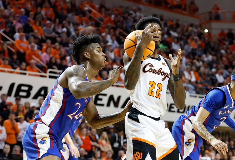 Feb 14, 2023; Stillwater, Oklahoma, USA; Oklahoma State Cowboys forward Kalib Boone (22) loses control of the ball in front of Kansas Jayhawks forward K.J. Adams Jr. (24) during the first half at Gallagher-Iba Arena. Mandatory Credit: Alonzo Adams-USA TODAY Sports