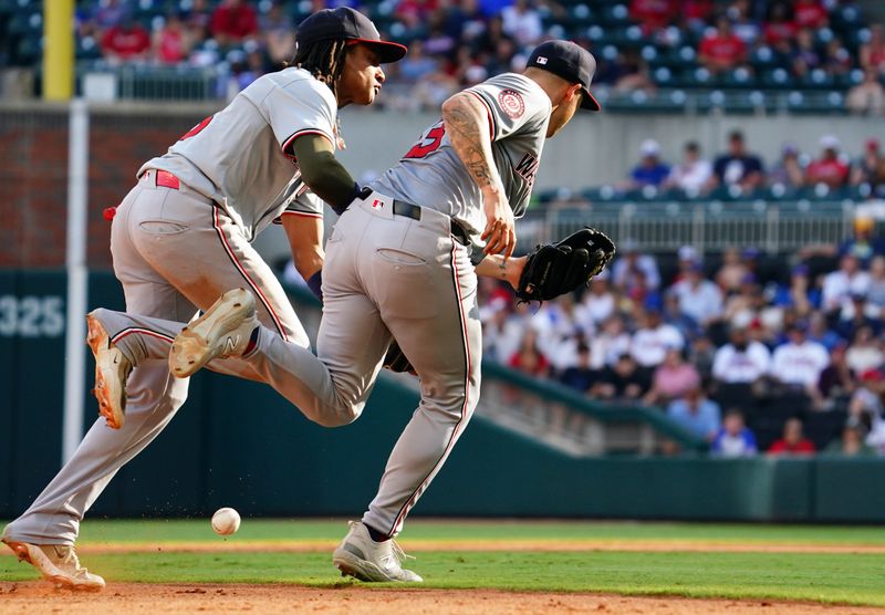 May 27, 2024; Cumberland, Georgia, USA; Atlanta Braves catcher Sean Murphy (12) hits an infield single on an error as Washington Nationals shortstop CJ Abrams (5) and Washington Nationals third baseman Nick Senzel (13) bobble the ball during the ninth inning at Truist Park. Mandatory Credit: John David Mercer-USA TODAY Sports