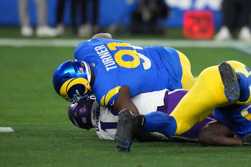 Los Angeles Rams defensive tackle Kobie Turner (91) sacks Minnesota Vikings quarterback Sam Darnold (14) during the first half of an NFL wild card playoff football game, Monday, Jan. 13, 2025, in Glendale, Ariz. (AP Photo/Ross D. Franklin)